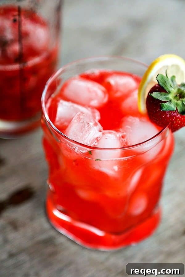 Strawberry Basil Lemonade Cocktail Recipe | Summer Boozy Drink 5 boozy strawberry basil lemonade, bormioli rocco sorgente highball glass, strawberry and lemon garnish, rustic wood table, vertical shot, glass cocktail shaker