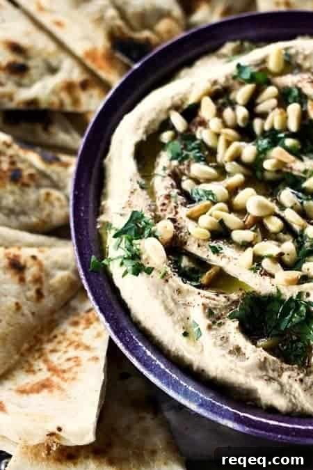 Crowd-Pleasing Party Hummus Recipe for Entertaining 2 Party Hummus - warm, silky, and topped with olive oil, pine nuts, za'atar, and parsley.
