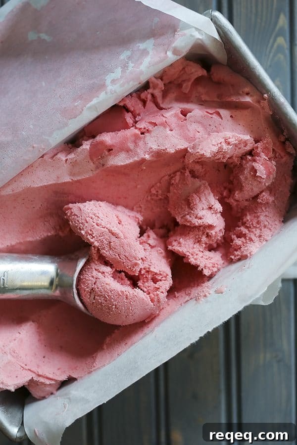 Creamy 3-Ingredient Strawberry Ice Cream Recipe 4 3-ingredient strawberry ice cream, parchment paper lined aluminum bread pan, rustic wooden table