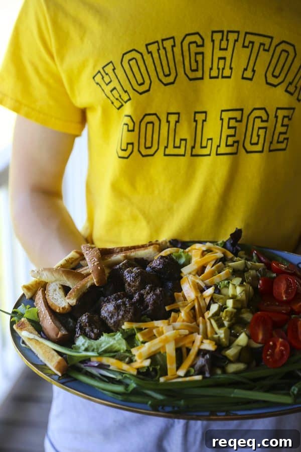 Cheeseburger Salad Recipe: Classic Burger Flavors in a Bowl 3 Cheeseburger Salad with sesame bun croutons, grilled meatballs, green onions, cheese, pickles, tomatoes, and fries.