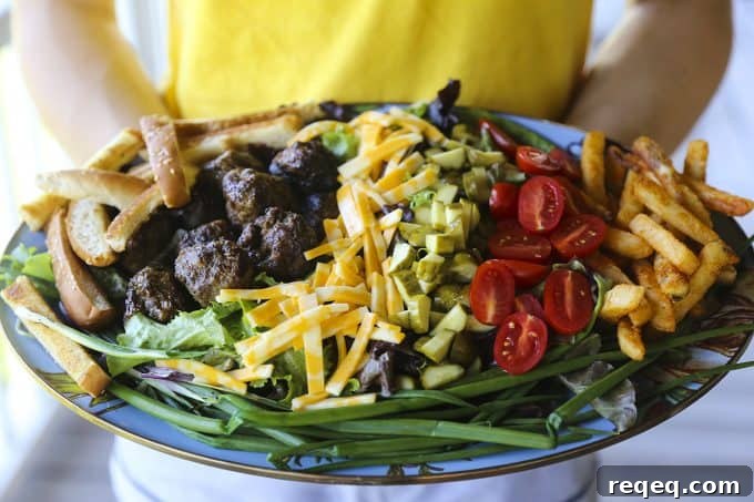 Cheeseburger Salad Recipe: Classic Burger Flavors in a Bowl 5 Cheeseburger Salad with sesame bun croutons, grilled meatballs, green onions, cheese, pickles, tomatoes, and fries.