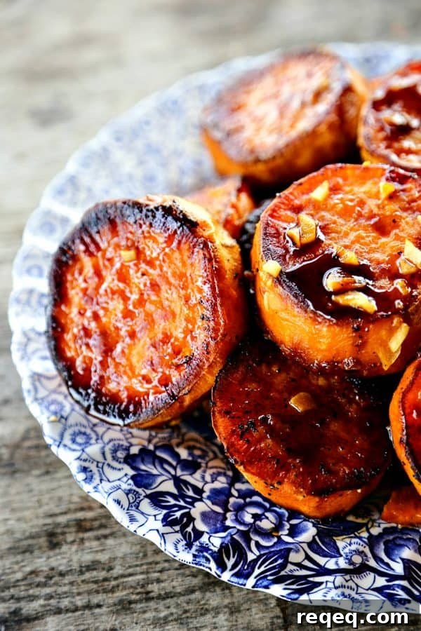 Creamy Baked Melting Sweet Potatoes with Brown Butter and Herbs 3 Melting Sweet Potatoes with sauce and garlic, thick roasted sweet potato rounds, caramelized, blue and white plate, on rustic wood table