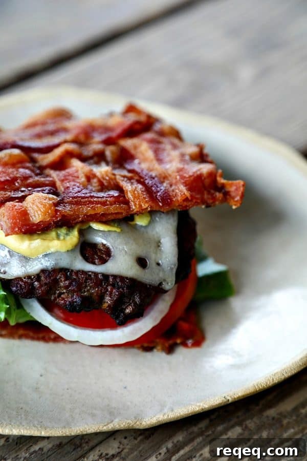 Low-Carb Swiss Bacon Burger Buns Recipe 2 Low-Carb Bacon Bun Swiss Burger with basket-weave bacon bun, Swiss cheese, ground chuck burger, Dijon mustard, lettuce, tomato, and onion.