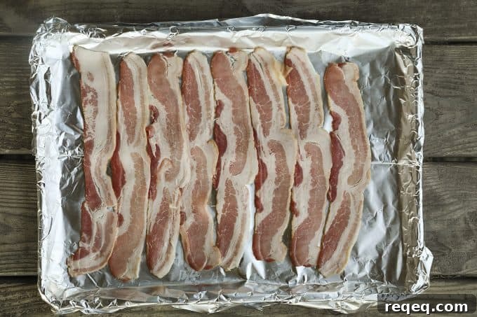Low-Carb Swiss Bacon Burger Buns Recipe 4 Bacon slices laid out on a foil-lined pan.