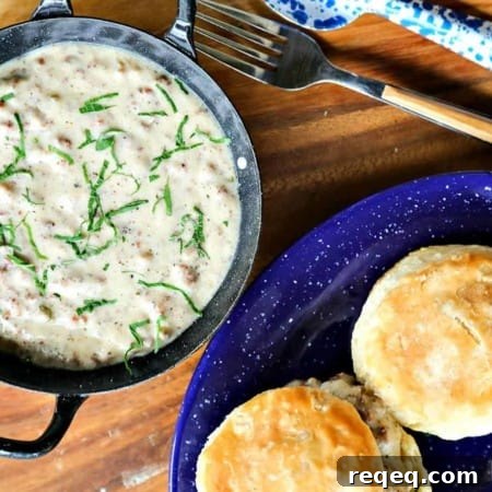 Classic Sausage Gravy in black and white enameled bowl with handles, biscuits on blue and white enamel plate
