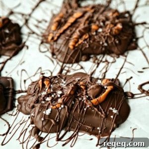 Chocolate Covered Caramel Stuffed Pretzels drizzled with caramel candy, chocolate, maldon sea salt flakes on parchment paper