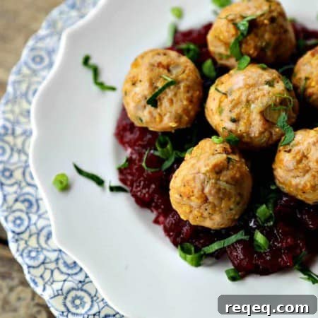 Turkey and stuffing meatballs, cranberry sauce, white target plate on antique blue and white scallopped plate, wooden background, 3/4 view, chopped parsley and green onions