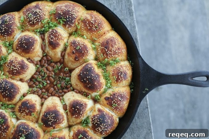 Cheeseburger Bombs Skillet with Baked Beans and Melty Cheese 2 Cheeseburger Bombs Baked Bean Skillet: rolls stuffed with meatballs and cheese baked around barbecue beans in a cast-iron skillet