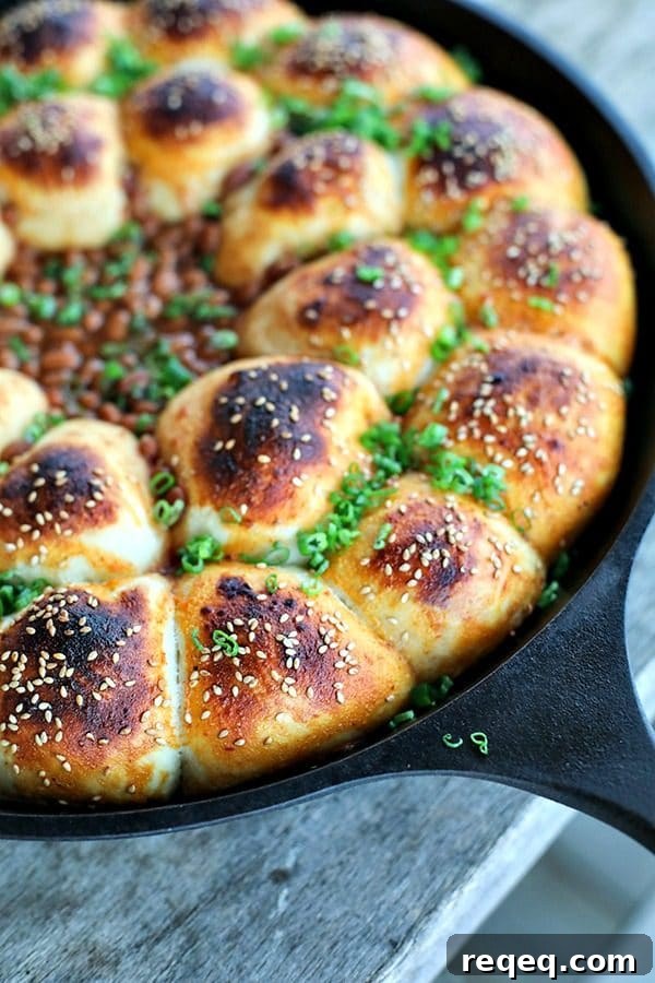 Cheeseburger Bombs Skillet with Baked Beans and Melty Cheese 3 Cheeseburger Bombs Baked Bean Skillet: close-up of sesame topped rolls stuffed with meatballs