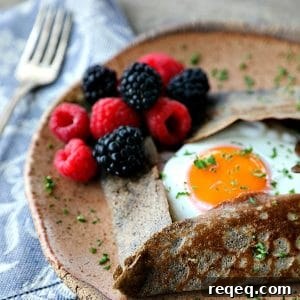 Buckwheat Crepes Recipe – Naturally Gluten Free Pancakes 6 Buckwheat Crepe with fried egg, ham, and cheese on a pottery plate that looks like wood, fresh blackberries, parsley garnish