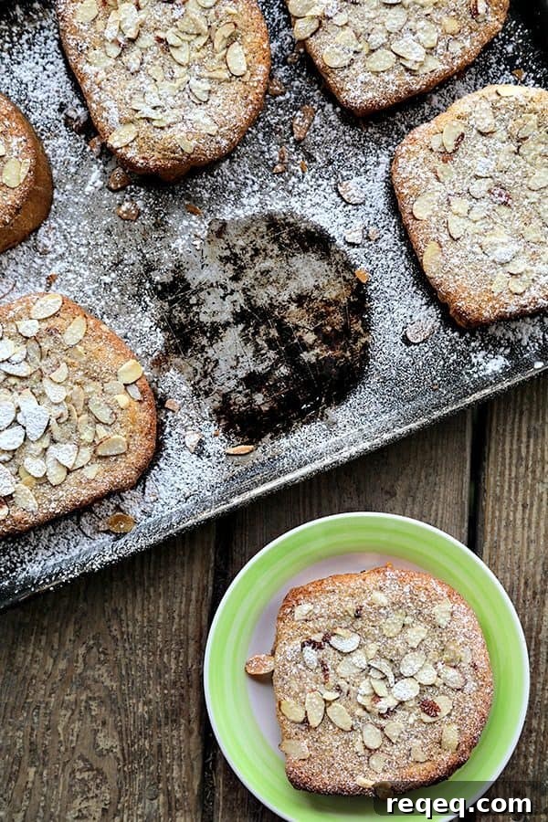 Nutella Raspberry Bostock: Almond-Crust Brioche Pastry 3 Antique Half sheet pan with Nutella Raspberry Bostock or brioche aux amandes, dusted with powdered sugar, one piece missing from the pan, one piece on an antique dessert plate with a bright green edge.