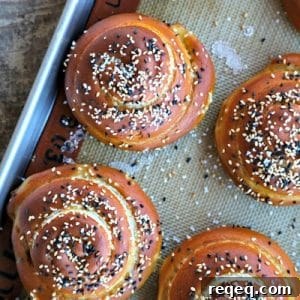 Soft pretzel rolls for sandwiches, silpat, half sheet pan, rustic wood table, sesame seeds, pretzel salt