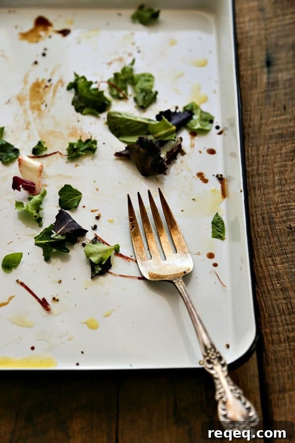 Bresaola and Parmesan Salad with Arugula and Lemon Dressing 4 antique fork, mostly empty serving Bresaola Parmesan Salad on white quarter sheet pan with cobalt blue rim, blue and white tea towel, rustic wood tabletop