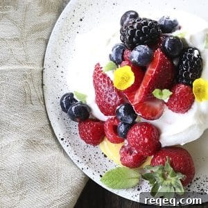 Ethereally light, crisp on the outside, marshmallowy on the inside, this Mini Pavlova Recipe is topped with lemon curd, berries, whipped cream, and ready for summer!