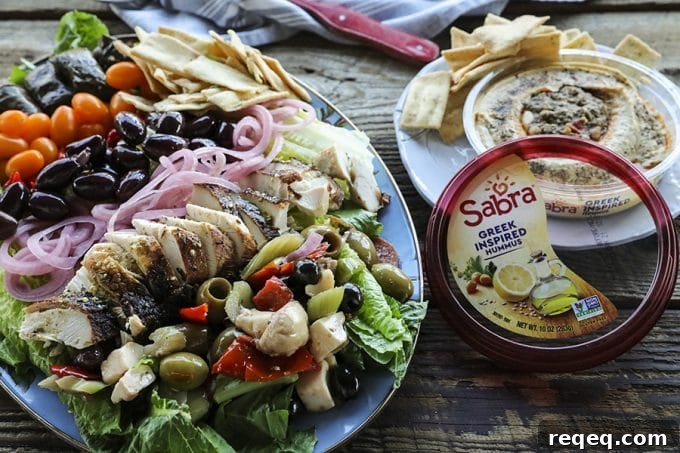 Greek Salad with lemon garlic chicken, marinated olive salad, quick pickled red onions, crumbled feta cheese, garlic stuffed kalamata olives, tiny grape tomatoes, stuffed grape leaves, Greek salad dressing, pita chips as croutons, and a hearty dollop of hummus.