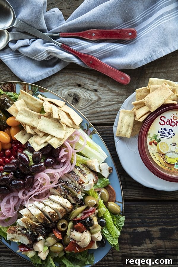 Greek Salad with lemon garlic chicken, marinated olive salad, quick pickled red onions, crumbled feta cheese, garlic stuffed kalamata olives, tiny grape tomatoes, stuffed grape leaves, Greek salad dressing, pita chips as croutons, and a hearty dollop of hummus.