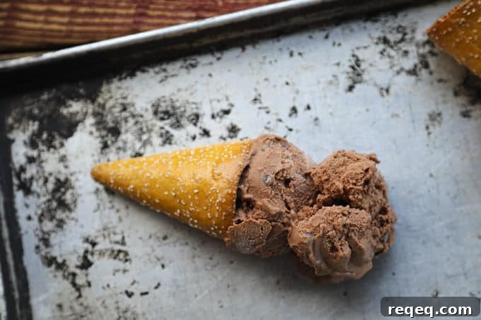 Two scoops of vegan dairy free chocolate ice cream in a pretzel cone on an antique sheet pan.