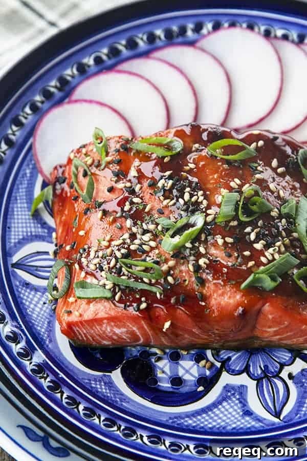 Air Fryer Salmon: Crispy, Tender Salmon in 12 Minutes 3 Glazed Salmon with sesame seeds and green onions, radishes, on a blue and white plate