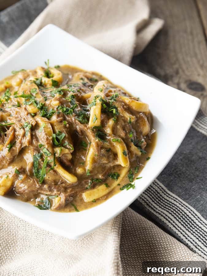 Slow Cooker Beef and Noodles Recipe for Comforting Weeknight Meals 2 crock pot beef and noodles in a white square bowl on linens