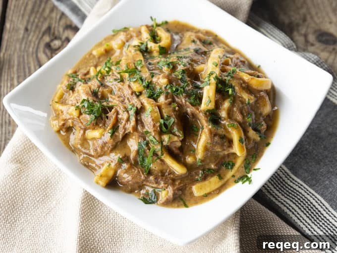 Slow Cooker Beef and Noodles Recipe for Comforting Weeknight Meals 6 crock pot beef and noodles in a white square bowl on linens
