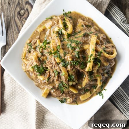 Slow Cooker Beef and Noodles Recipe for Comforting Weeknight Meals 7 crock pot beef and noodles in a white square bowl on linens