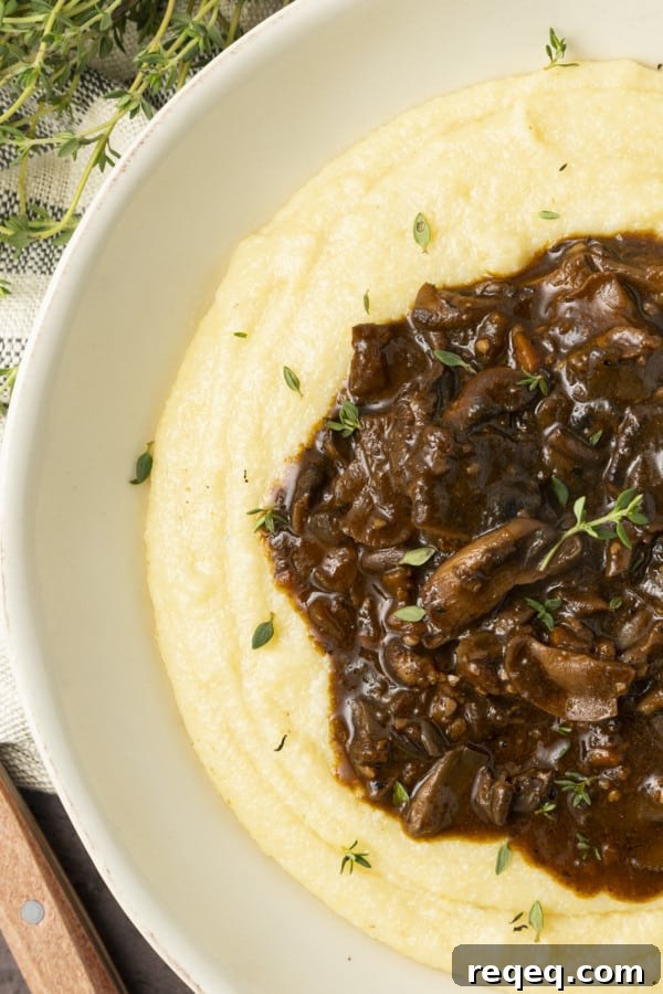Hearty Mushroom Stew Recipe for Cozy Weeknight Dinners 2 Mushroom stew over polenta in a pottery bowl with thyme nearby.