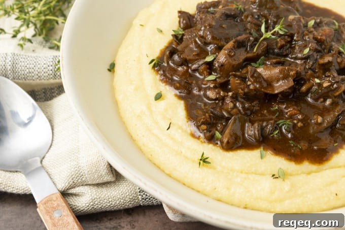 Hearty Mushroom Stew Recipe for Cozy Weeknight Dinners 3 Mushroom stew over polenta in a pottery bowl with thyme nearby.