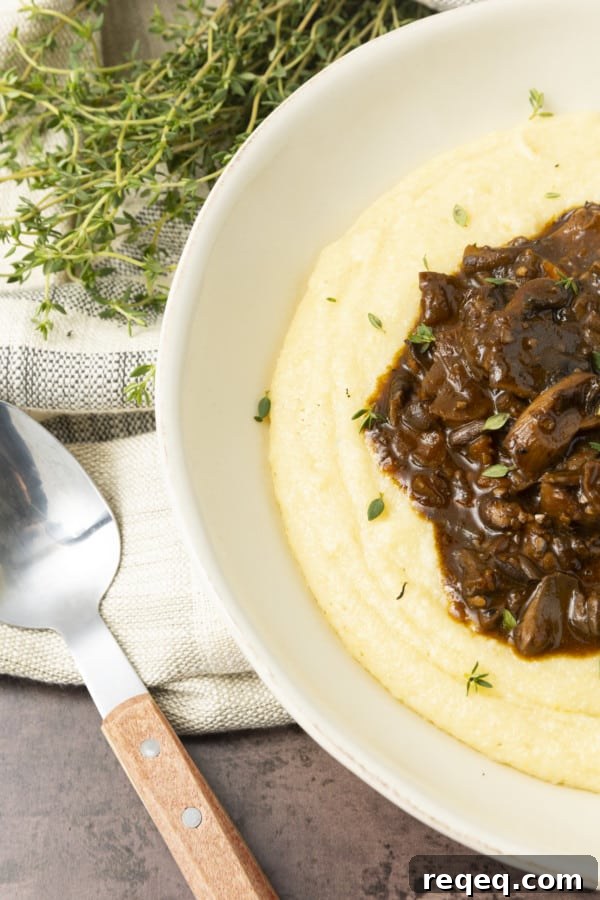 Hearty Mushroom Stew Recipe for Cozy Weeknight Dinners 4 Mushroom stew over polenta in a pottery bowl with thyme nearby.