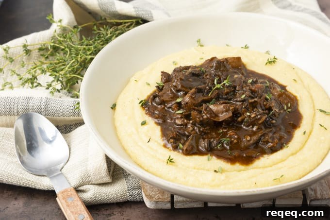 Hearty Mushroom Stew Recipe for Cozy Weeknight Dinners 5 Mushroom stew over polenta in a pottery bowl with thyme nearby.