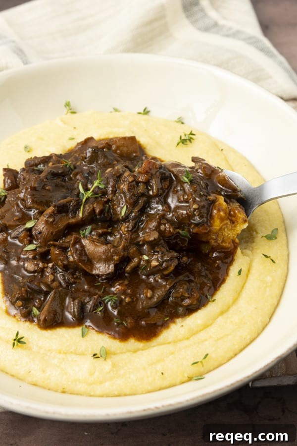 Hearty Mushroom Stew Recipe for Cozy Weeknight Dinners 6 Mushroom stew over polenta in a pottery bowl with thyme nearby.