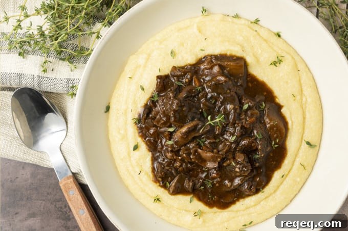 Hearty Mushroom Stew Recipe for Cozy Weeknight Dinners 7 Mushroom stew over polenta in a pottery bowl with thyme nearby.