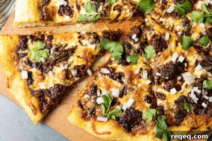 Birria Pizza: Chewy crust topped with tender shredded birria beef, smoky birria stew, loads of melted cheese, chopped sweet onion, fresh cilantro, a squeeze of fresh lime, and a bowl of red chile sauce for dipping.