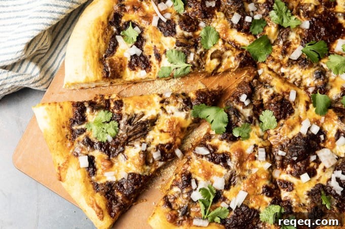 Birria Pizza: Chewy crust topped with tender shredded birria beef, smoky birria stew, loads of melted cheese, chopped sweet onion, fresh cilantro, a squeeze of fresh lime, and a bowl of red chile sauce for dipping.