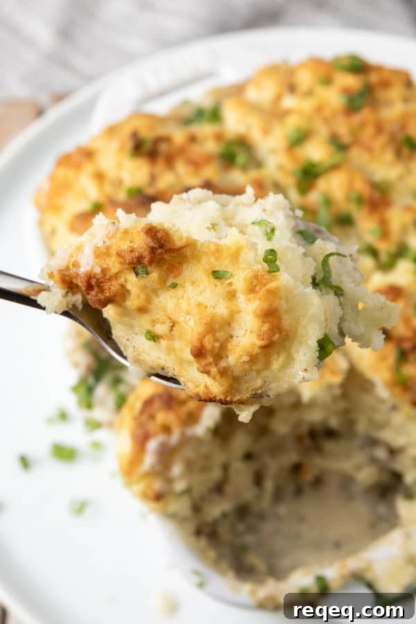 Savory Sausage Gravy Breakfast Casserole 6 small white casserole dish filled with sausage gravy and topped with buttermilk biscuit crust on top of a plate with a spoon in it.