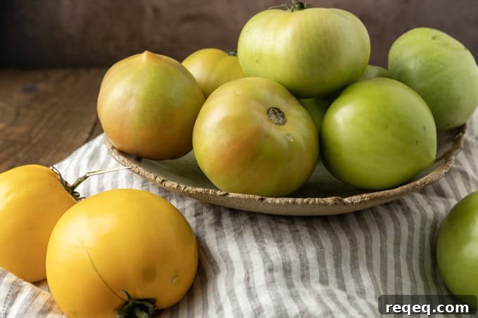 Crispy Air Fryer Fried Green Tomatoes — Quick Southern Recipe 4 green tomatoes in a pottery bowl with a taupe and white striped linen