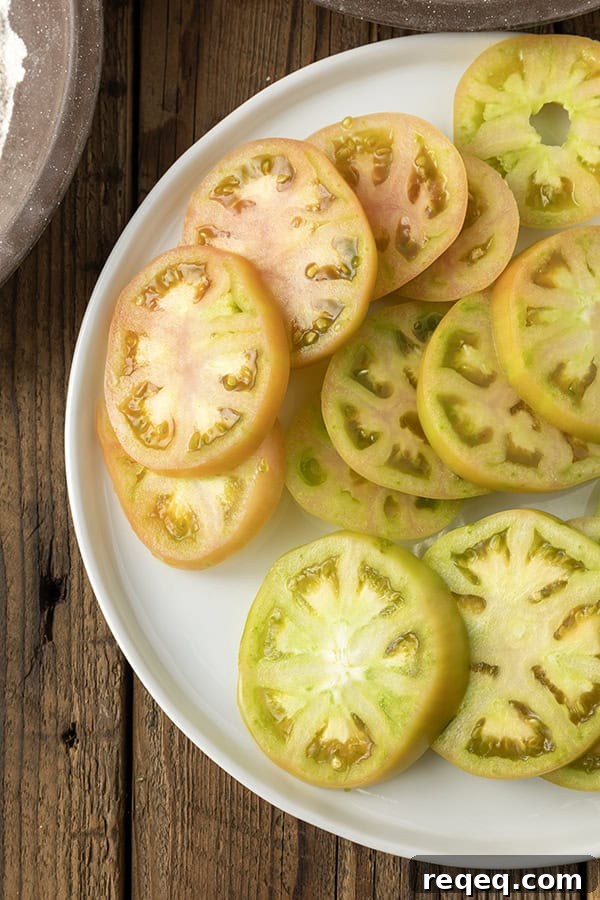 Crispy Air Fryer Fried Green Tomatoes — Quick Southern Recipe 5 Sliced green tomatoes on a white plate on a rustic wooden table
