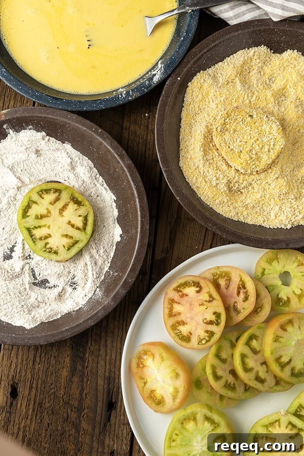 Crispy Air Fryer Fried Green Tomatoes — Quick Southern Recipe 6 Sliced green tomatoes on a white plate with three stage breading ingredients in enamel pie plates
