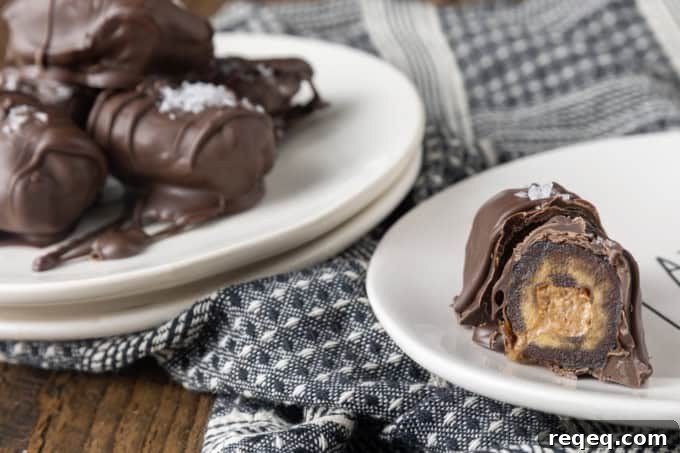 Chocolate-Covered Dates: Simple Recipe for Decadent Treats 2 cross cut almond butter stuffed medjool dates covered in chocolate and sprinkled with sea salt on small white plates with a blue and white linen