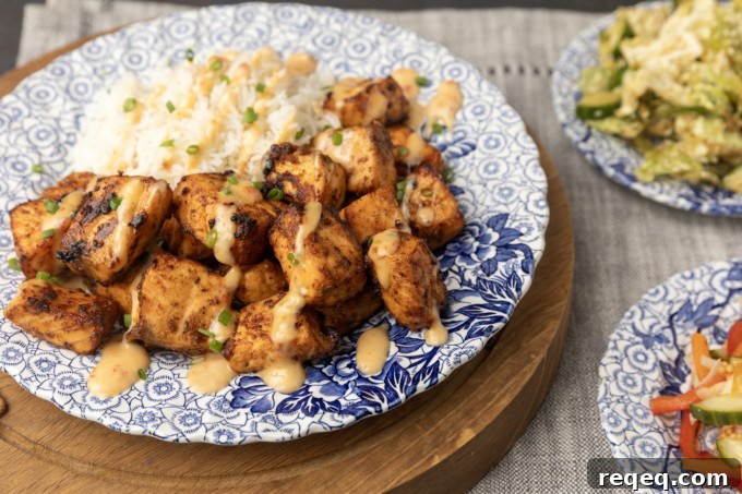 Crispy Bang Bang Salmon Bites Recipe for Spicy Sweet Salmon Bites 4 crispy air fryer bang bang salmon bites drizzled with sauce served with ice on a blue and white floral plate