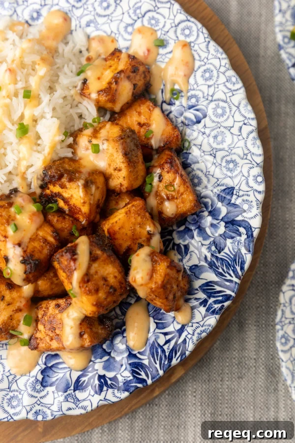 Crispy Bang Bang Salmon Bites Recipe for Spicy Sweet Salmon Bites 5 crispy air fryer bang bang salmon bites drizzled with sauce served with ice on a blue and white floral plate