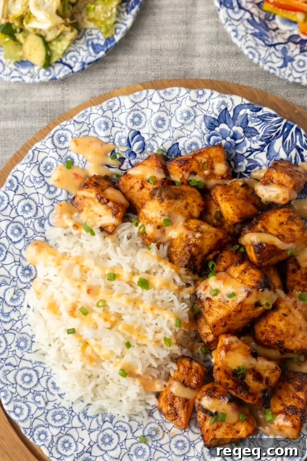 Crispy Bang Bang Salmon Bites Recipe for Spicy Sweet Salmon Bites 6 crispy air fryer bang bang salmon bites drizzled with sauce served with ice on a blue and white floral plate