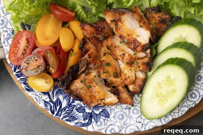 Juicy Pellet-Grilled Chicken Thighs: Flavorful Weeknight Recipe 2 chicken thighs grilled on a pellet grill on a plate with lettuce, tomatoes, and cucumbers
