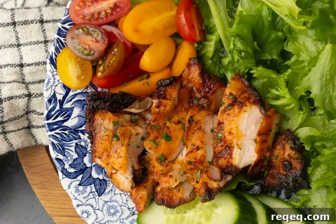 Juicy Pellet-Grilled Chicken Thighs: Flavorful Weeknight Recipe 4 chicken thighs grilled on a pellet grill on a plate with lettuce, tomatoes, and cucumbers