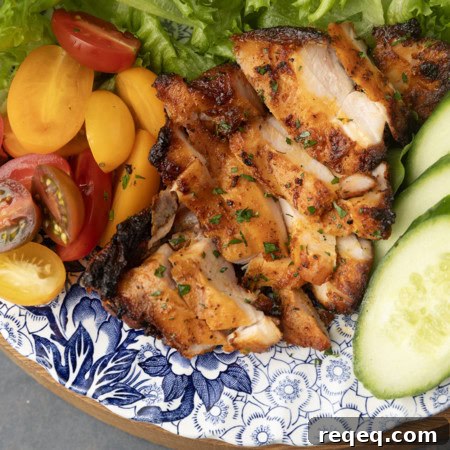 Juicy Pellet-Grilled Chicken Thighs: Flavorful Weeknight Recipe 6 chicken thighs grilled on a pellet grill on a plate with lettuce, tomatoes, and cucumbers