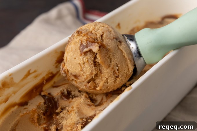 Creamy Dulce de Leche Ice Cream Recipe – Homemade Argentine Flavor 2 A scoop of dulce de leche ice cream is being scooped into a bowl.