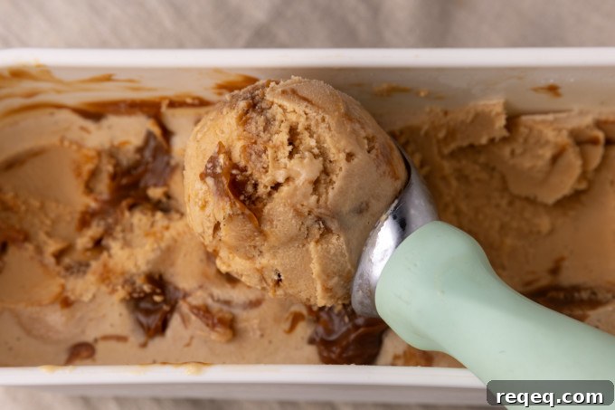 Creamy Dulce de Leche Ice Cream Recipe – Homemade Argentine Flavor 4 A scoop of dulce de leche ice cream with caramel sauce on top.