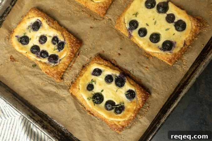 Flaky Cream Cheese Pastries: Quick Recipe for Homemade Treats 3 blueberry cream cheese puff pastry with thyme on parchment lined pan