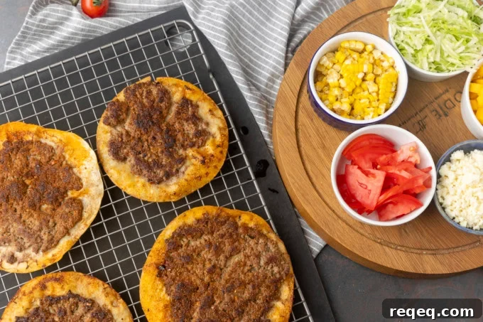 smash tacos on a cooling rack with toppings in bowls