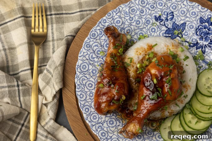 baked honey garlic chicken on rice with cucumbers on a blue and white plate