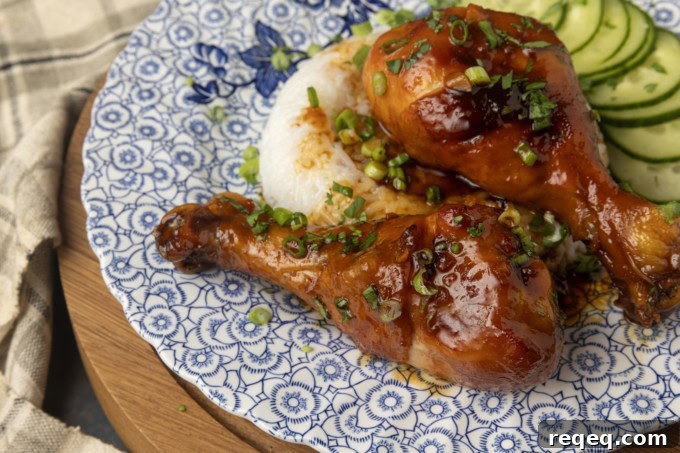 baked honey garlic chicken on rice with cucumbers on a blue and white plate